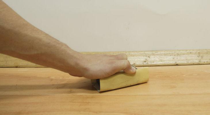 В первую очередь прошкуриваем поверхность линолеума